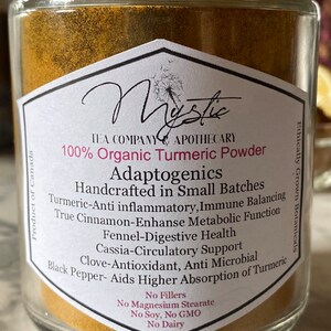May include: A glass jar filled with golden turmeric powder. The label reads "100% Organic Turmeric Powder Adaptogenics Handcrafted in Small Batches" and lists the benefits of turmeric, including anti-inflammatory, immune balancing, and digestive health. The label also states "No Fillers, No Magnesium Stearate, No Soy, No GMO, No Dairy".