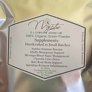 May include: A white bag with a green label that reads "Mystic Tea Company Apothecary 100% Organic Green Powder Supplements Handcrafted in Small Batches" and lists the benefits of the product, including "Nettles-Immune Booster", "Alfalfa-Menopause Support", "Moringa-Blood Sugar Management", "Chorella-Liver Detox", "Beet Root-Brain Support", and "Spirulina-Reduces Inflammation". The label also states "No Fillers", "No Magnesium Stearate", "No Soy, No GMO", and "No Dairy". The bag is labeled "Ethically Grown Botanicals" and "Product of Canada".