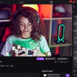 Może przedstawiać: Zrzut ekranu z transmisji Twitch z kobietą w słuchawkach i mikrofonie, uśmiechniętą podczas patrzenia na telefon. Stream wyświetla nazwę użytkownika "pixlin" i zawiera animowaną grafikę kot&oacute;w. Interfejs pokazuje czat i informacje o streamie.