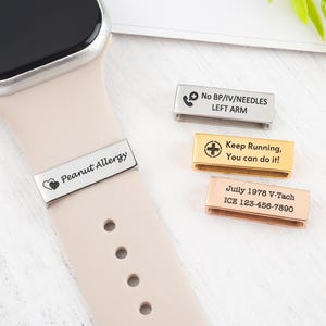 Könnte beinhalten: Eine beige Smartwatch mit passendem Armband, mit einem silbernen Band mit dem Text "Peanut Allergy" und Herzsymbolen. Zusätzliche Metallbänder mit medizinischen Informationen werden angezeigt, darunter "No BP/IV/NEEDLES LEFT ARM".