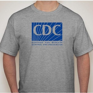 May include: A gray t-shirt with the CDC logo in blue. The logo says "Centers for Disease Control and Prevention".
