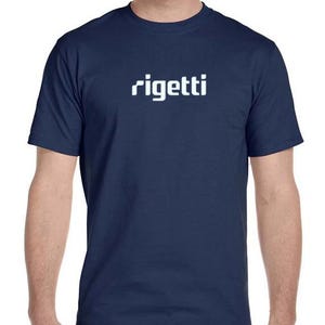 May include: Navy blue t-shirt with the white word "rigetti" across the chest. The shirt is a crew neck style and appears to be made of a soft, comfortable material. The model is wearing blue jeans.