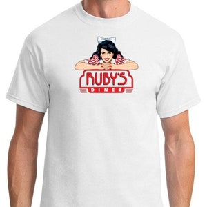May include: White t-shirt with a red and white logo for Ruby's Diner. The logo features a cartoon woman with a red bow in her hair and the text "Ruby's Diner".