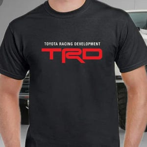 May include: Black t-shirt with white text that reads "TOYOTA RACING DEVELOPMENT" and a red logo that reads "TRD"