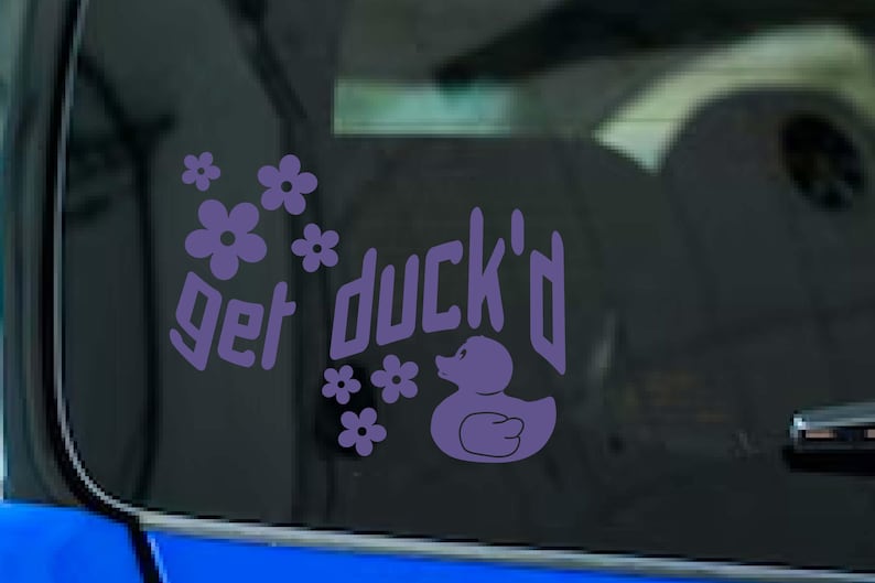 May include: Purple vinyl decal with the phrase "get duck'd", a duck illustration, and floral accents. The decal is designed to be applied to a car window or similar surface.