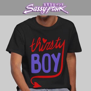 May include: Black t-shirt with the words "thirsty BOY" in red and purple. The word "thirsty" has a heart above the letter "i". The shirt also has the text "Sassy FUNK" in a purple, stylized font.