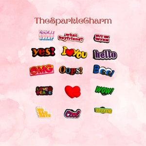 May include: A set of 14 colorful shoe charms with various phrases and designs, including "You're Doing Great", "What Boyfriend?", "Out of Office", "Yes!", "I Love You", "Hello", "OMG", "Oops!", "Boo!", "Love & Peace", "Wow!", "No Bad Days", "Cool", and "Weekend".