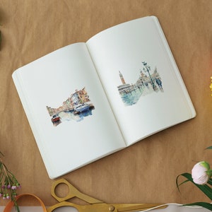May include: An open sketchbook with two watercolor illustrations of Venice, Italy. The left page shows a canal with boats and buildings. The right page shows a street scene with a tall building and people walking.