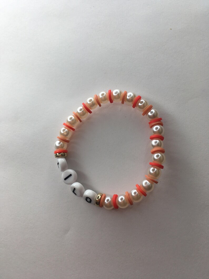 May include: A white pearl bracelet with red and orange beads spelling out the word "LOL".
