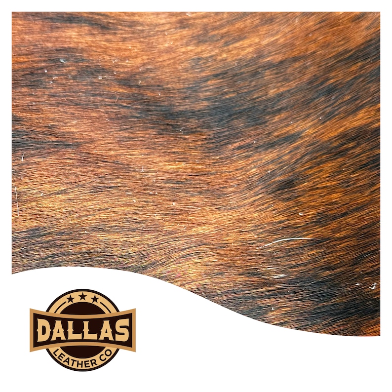 May include: Close-up of a brown and black cowhide with a wavy pattern. The hide has a natural, rustic look. The Dallas Leather Co. logo is in the bottom left corner.