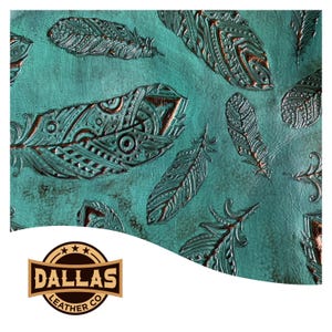 May include: A teal leather sheet featuring an embossed pattern of various feathers with copper-toned highlights. The surface displays a weathered texture. A logo in the corner reads DALLAS LEATHER CO with three stars above the text in a circular frame.