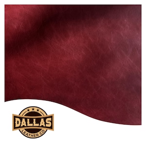 Może przedstawiać: Zbliżenie kawałka bordowej skóry o teksturowanej powierzchni. Skóra ma bogaty, głęboki kolor i subtelne odcienie. Logo Dallas Leather Co. znajduje się w lewym dolnym rogu.