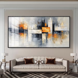 Op de afbeelding: Abstract schilderij met een modern ontwerp met geometrische vormen in grijstinten, wit en oranje. Het schilderij is ingelijst en hangt aan een muur boven een witte bank.