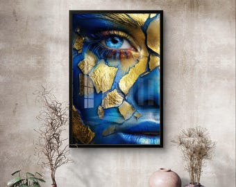 Peut inclure: Œuvre d'art encadrée représentant un gros plan d'un visage à la peau bleue et à un œil bleu saisissant. Des accents de feuilles d'or ornent le visage, créant un effet artistique texturé. L'œuvre est exposée sur un mur aux tons neutres.