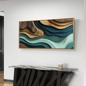 Puede incluir: Arte mural abstracto con marco dorado. La obra presenta texturas en capas en tonos marrón, verde azulado y verde, creando una sensación de profundidad. Está montada en una pared blanca sobre una consola moderna.