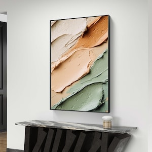 May include: Abstract art print with a black frame, featuring a colorful painting of green, orange, and white paint strokes. The print is displayed on a black marble console table with a unique geometric design.