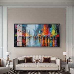 Könnte beinhalten: Ein großes, rechteckiges, gerahmtes Gemälde, das eine farbenfrohe Stadtlandschaft mit Reflexionen darstellt. Das Kunstwerk zeigt lebendige Farbtöne von Rot, Orange, Blau und Grün, was auf eine regnerische Nachtszene mit Regenschirmen und Stadtlichtern hindeutet.