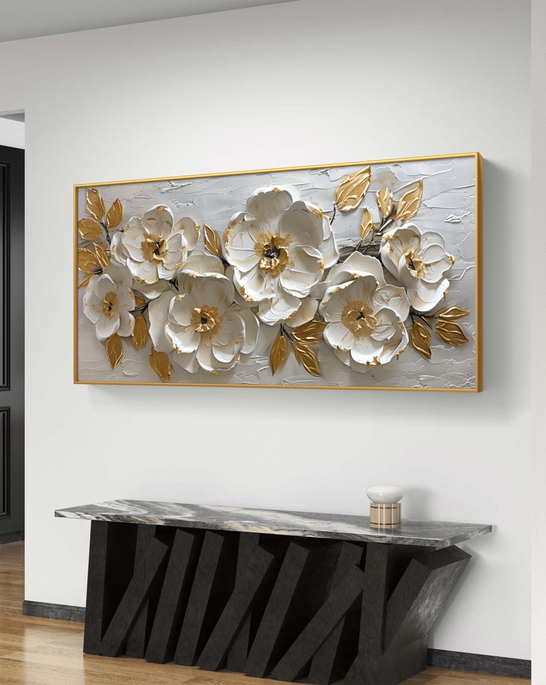 May include: A large, rectangular canvas painting with a gold frame. The painting features a white floral design with gold accents. The flowers are in a 3D style, giving the painting a textured look.