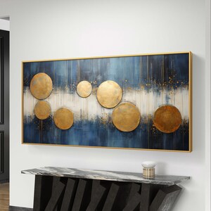 Pode incluir: Pintura abstrata com fundo azul e branco e círculos dourados. A pintura é emoldurada em uma moldura dourada.