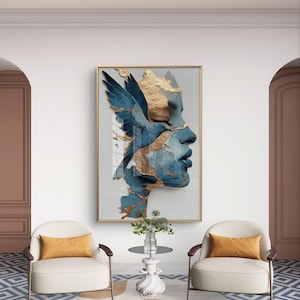 Könnte beinhalten: Abstrakte Wandkunst mit einem Gesichtsprofil mit blauen und goldenen Akzenten. Das Kunstwerk hat ein flügelartiges Design und ist goldgerahmt. Das Bild wird in einem modernen Wohnzimmer mit zwei Sesseln und einem kleinen Tisch gezeigt.