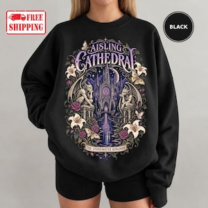 May include: A black crewneck sweatshirt featuring a graphic print of a gothic cathedral, gargoyles, lilies, roses, and moths. The text reads AISLING CATHEDRAL and THE STONEWATER KINGDOM. The design includes purple, white, and green accents.