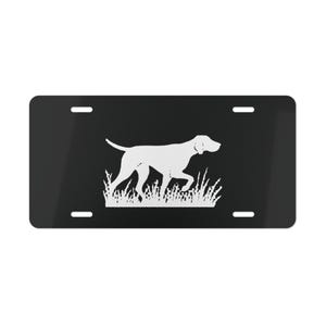 Könnte beinhalten: Schwarzes Nummernschild mit einer weißen Silhouette eines Hundes, wahrscheinlich ein Pointer, in einem Grasfeld. Das Design ist minimalistisch. Die Platte hat vier Befestigungslöcher. Der Hund geht.