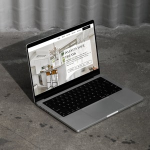 May include: A laptop computer displaying a website with the text "Invest in your dreams". The website features a photo of a modern kitchen with white cabinets, a stainless steel refrigerator, and a large chandelier.