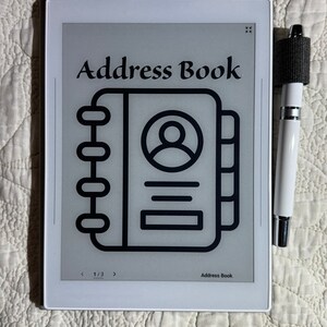 May include: A white e-reader with a black and white icon of an address book on the screen. The screen also displays the text "Address Book" and "1/3".