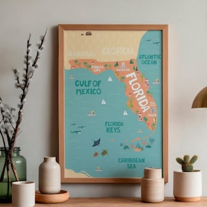 Puede incluir: Un mapa enmarcado de Florida, con el contorno del estado en naranja sobre un fondo turquesa. El mapa incluye etiquetas para ciudades, el Golfo de México, el Océano Atlántico y los Cayos de Florida. El marco es de madera marrón claro.