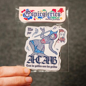 Puede incluir: Un paquete transparente de pegatinas con ilustraciones de estilo medieval. Las pegatinas incluyen un caballero, una cabeza cortada y el texto "ACAB" en azul gótico. El paquete tiene el texto "Espiegleries adhesives".