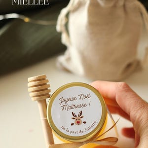 Pot de miel artisanal personnalisé avec étiquette 'Joyeux Noël Maîtresse', décoré d’un ruban beige et d’une cuillère en bois. Cadeau local et unique pour Noël, parfait pour remercier les maîtresses . Produit dans la Drôme