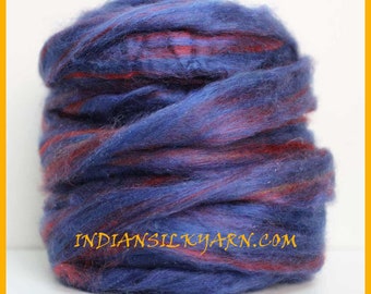 May include: A bundle of blue yarn with red streaks. The yarn appears soft and textured, with the text INDIANSILKYARN.COM visible. The colors blend together, creating a visually appealing textile. This yarn is suitable for various craft projects.