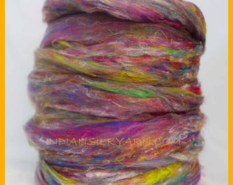 May include: A close-up of a vibrant, multi-colored yarn spool. The yarn is a blend of purple, pink, yellow, green, and orange hues. The text "INDIANSILKYARN.COM" is visible on the yarn. This yarn is suitable for various crafting projects.