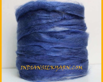 May include: A tightly wound bundle of deep blue silk yarn. The yarn has a soft, textured appearance with subtle variations in color, creating a layered effect. The text "INDIANSILKYARN.COM" is visible on the yarn.