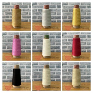 Può includere: Una collezione di nove rocchetti di filo in vari colori, tra cui oro, argento, giallo, rosa, crema, rosso, nero e bianco sporco. Ogni rocchetto è cilindrico con una parte superiore a motivi e presenta il testo IndianSilkYarn.com alla base.