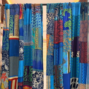 Puede incluir: Cortinas de patchwork en tonos azules y morados. Las cortinas están hechas de varias piezas de tela con diferentes patrones, incluyendo diseños florales, geométricos y abstractos. Cuelgan de una barra y cubren parcialmente una ventana.