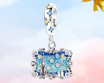 May include: A silver dangle charm featuring a rectangular frame with blue enamel, depicting a night sky with stars, a crescent moon, and stylized trees. The bail is decorated with small blue and yellow stones set in star-shaped metal cutouts.