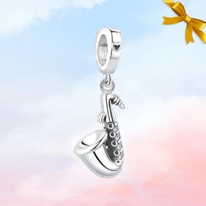 Peut inclure: Un charm en forme de saxophone de couleur argentée avec une finition polie et des détails de clés. Le bijou comprend une bélière sur le dessus avec une petite gravure en forme de cœur, conçu pour être suspendu à un bracelet ou une chaîne.