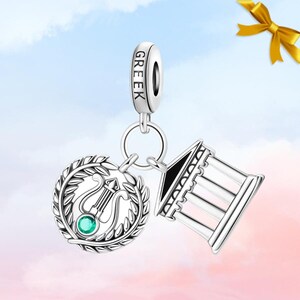 May include: Silver charm with the word "GREEK" engraved on the top. The charm features a lyre within a laurel wreath and a miniature temple. The lyre has a green gemstone. The charm is designed to be a pendant.