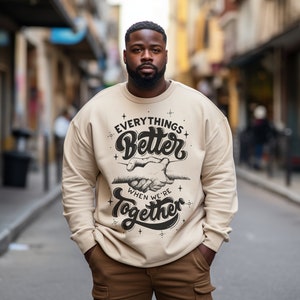May include: A beige sweatshirt with a black graphic print that says "Everything's Better When We're Together" with a hand shake graphic.