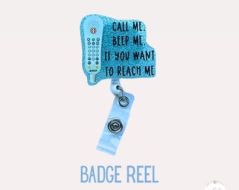 May include: A light blue glitter badge reel with a retro phone design. The text on the badge reel says "CALL ME, BEEP ME, IF YOU WANT TO REACH ME". The badge reel has a white strap and a metal snap closure. The words "BADGE REEL" are written in blue.