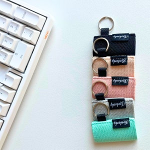 Peut inclure: Cinq porte-cl&eacute;s color&eacute;s avec des anneaux argent&eacute;s et le mot "Cooyoooh" imprim&eacute; sur chacun. Les porte-cl&eacute;s sont noir, p&ecirc;che, rose, gris et bleu clair.