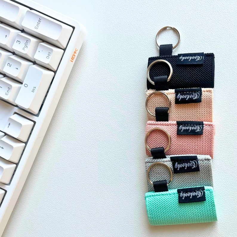Peut inclure: Cinq porte-cl&eacute;s color&eacute;s avec des anneaux argent&eacute;s et le mot "Cooyoooh" imprim&eacute; sur chacun. Les porte-cl&eacute;s sont noir, p&ecirc;che, rose, gris et bleu clair.