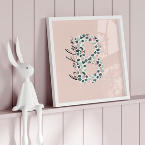 Puede incluir: Una impresión enmarcada en blanco con un fondo rosa y una gran letra "B" en un patrón de estampado animal verde, rosa y blanco. El nombre "brooklyn" está escrito en cursiva debajo de la letra.