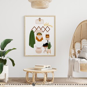 May include: A framed print with a welcome sign, a black cat, a plant, and a basket on a wooden rack. The print is in a modern style with a minimalist aesthetic.