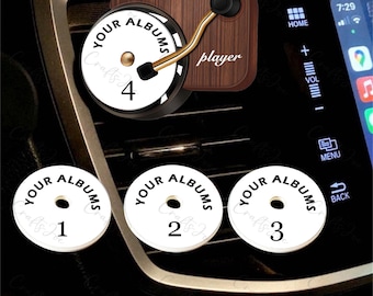 Op de afbeelding: Een auto-luchtverfrisser ontworpen als een miniatuur platenspeler met een basis in houtnerf en een gouden toonarm. Het bevat vier ronde witte inzetstukken met het opschrift 'YOUR ALBUMS' en de zwarte cijfers 1, 2, 3 en 4.