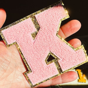 Puede incluir: Letra K de fieltro rosa con un contorno de purpurina dorada. La letra mide aproximadamente 12,5 cm de alto y 10 cm de ancho.