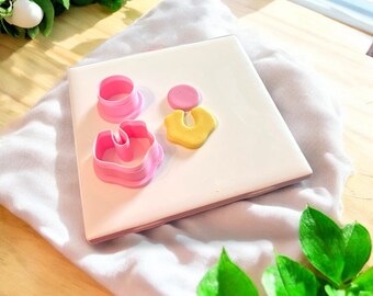 Könnte beinhalten: Rosa und gelbe Polymer Clay Ohrringe auf einer weißen Oberfläche mit rosa und weißen Ausstechern.