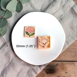 May include: Two square cookie stamps with a floral design. One stamp is a finished product with a pink flower and green leaves. The other is a mold of the same design. The text "32mm (1.25")" is below the stamps.