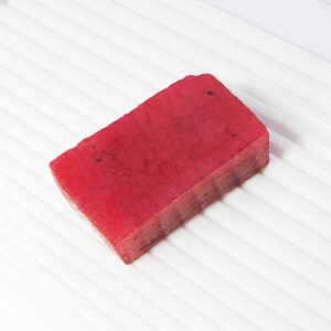 Peut inclure: Une barre de savon rouge rectangulaire avec une apparence marbrée.
